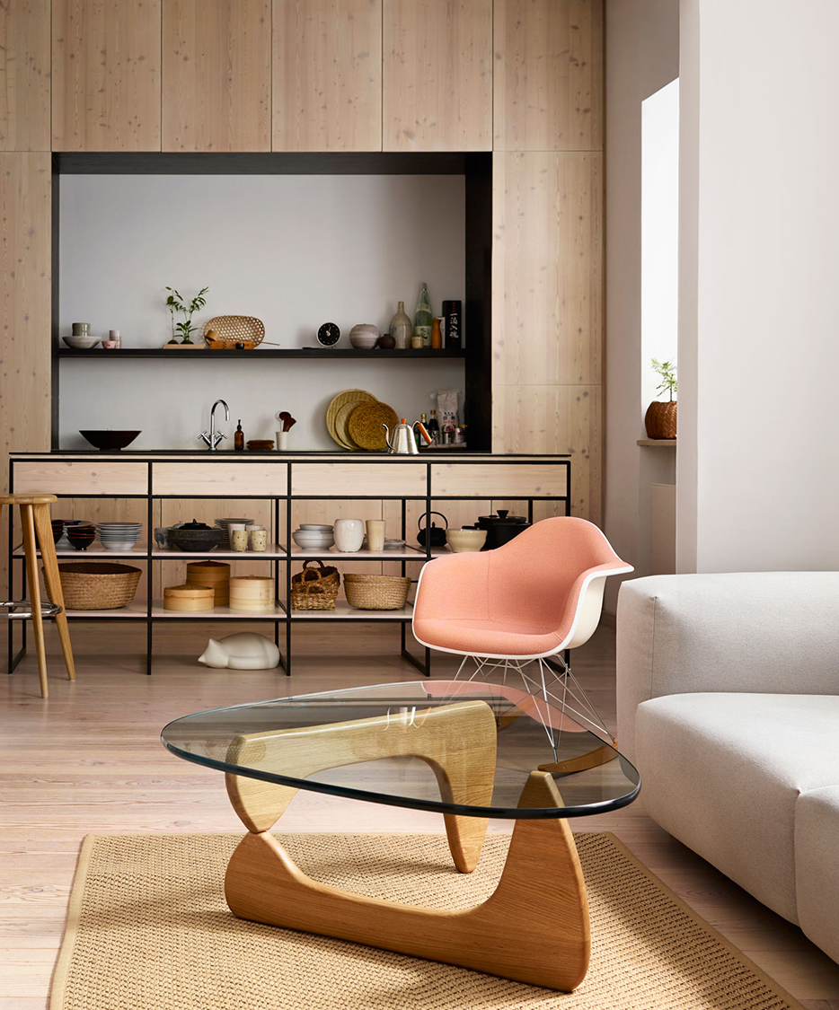Innist sculptural coffee table in light ash, lifestyle setting with biomorphic wooden base and tempered glass top